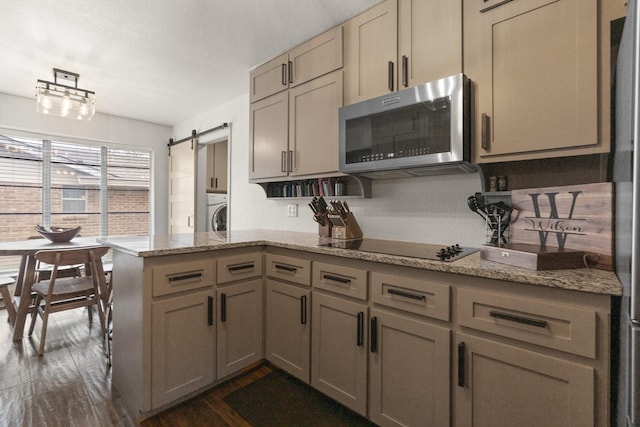 kitchen with a peninsula, dark wood-style floors, black electric cooktop, washer / dryer, and stainless steel microwave