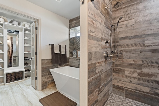 full bath with a soaking tub, tile walls, tiled shower, and a walk in closet