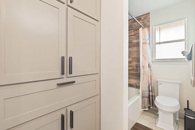 full bathroom featuring toilet, shower / bathtub combination with curtain, and wood finished floors