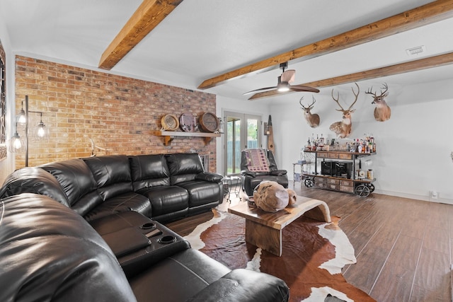 living room with wood finished floors, visible vents, brick wall, beamed ceiling, and ceiling fan