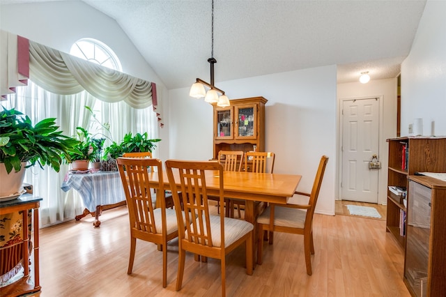 dining room with light wood finished floors and vaulted ceiling