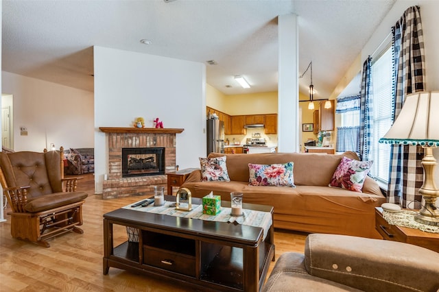 living room with light wood-type flooring, a brick fireplace, and lofted ceiling