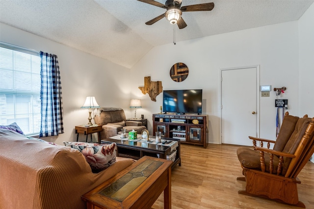 living area featuring light wood-type flooring, a ceiling fan, vaulted ceiling, and a textured ceiling