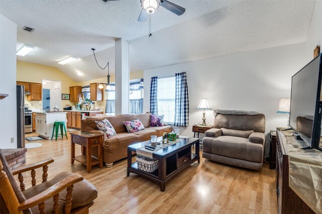 living area featuring light wood-style flooring, a textured ceiling, a ceiling fan, visible vents, and lofted ceiling
