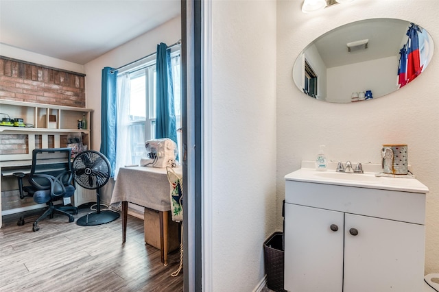 bathroom with ensuite bath, vanity, and wood finished floors
