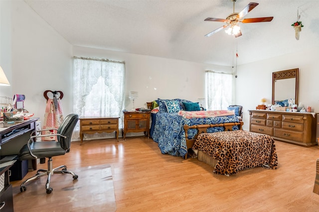 bedroom with ceiling fan, light wood finished floors, and vaulted ceiling
