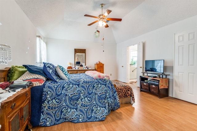 bedroom featuring a textured ceiling, multiple windows, wood finished floors, and lofted ceiling