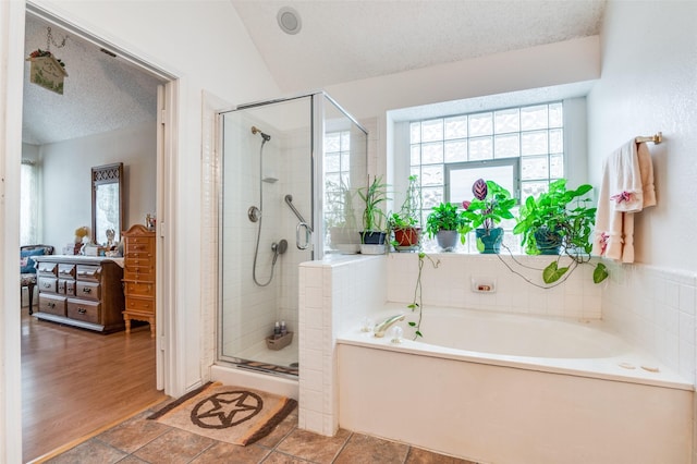 full bathroom with a stall shower, a garden tub, lofted ceiling, and plenty of natural light