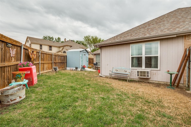 view of yard with an outbuilding, a storage unit, a fenced backyard, and a wall mounted air conditioner