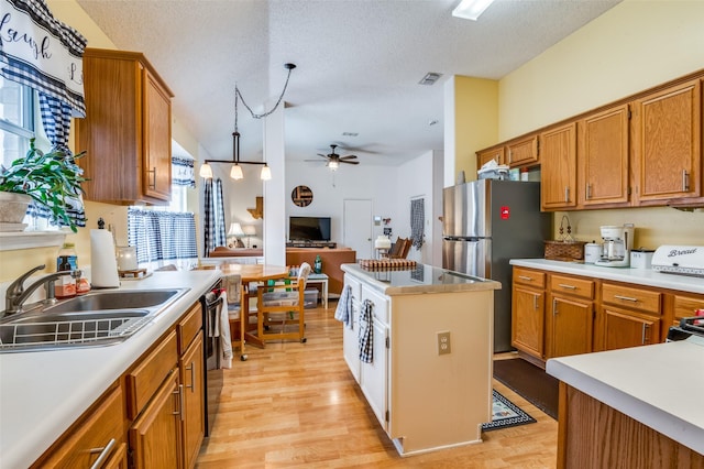 kitchen featuring visible vents, a sink, light countertops, a ceiling fan, and light wood finished floors