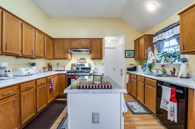 kitchen featuring vaulted ceiling, gas range, dishwasher, a sink, and under cabinet range hood