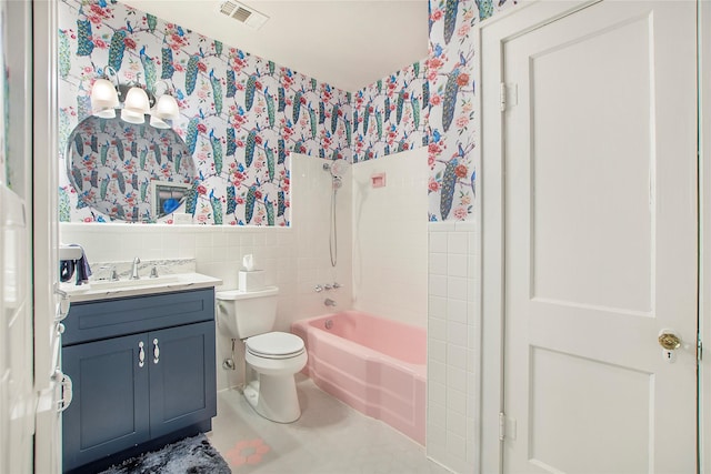 bathroom with wallpapered walls, toilet, tile walls, and wainscoting
