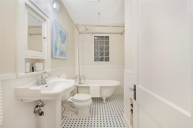 full bath with a wainscoted wall, a freestanding bath, and toilet