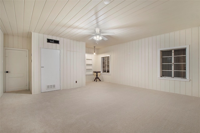 carpeted spare room featuring visible vents and a ceiling fan