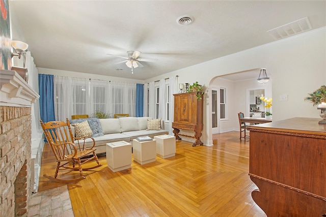 living area featuring visible vents, crown molding, arched walkways, and ceiling fan
