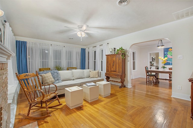 living room with arched walkways, baseboards, visible vents, and a ceiling fan