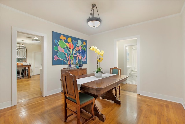 dining area featuring baseboards, light wood-style flooring, and crown molding