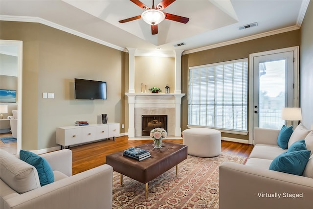2212 Stone Creek Dr, Mckinney, TX 75072 - living room with wood finished floors, a ceiling fan, a tile fireplace, a raised ceiling, and crown molding