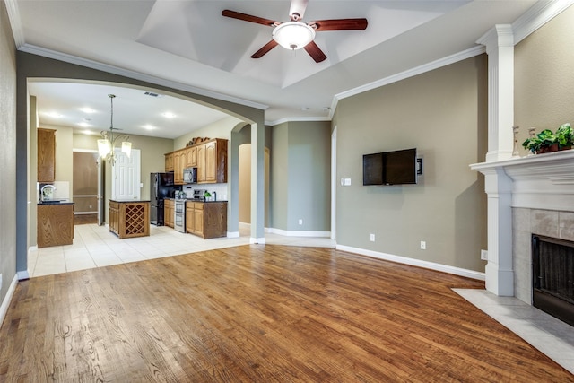 2212 Stone Creek Dr, Mckinney, TX 75072 - unfurnished living room with arched walkways, ceiling fan, a tile fireplace, a tray ceiling, and light wood finished floors