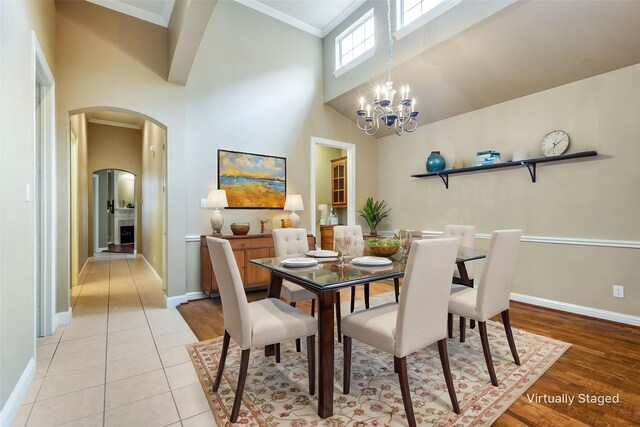 2212 Stone Creek Dr, Mckinney, TX 75072 - dining space featuring arched walkways, a high ceiling, baseboards, a chandelier, and light wood-style floors