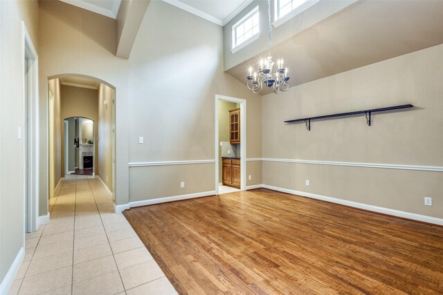 2212 Stone Creek Dr, Mckinney, TX 75072 - empty room featuring arched walkways, a towering ceiling, ornamental molding, baseboards, and a chandelier