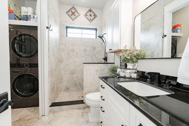 full bath featuring vanity, toilet, marble finish floor, stacked washer and dryer, and walk in shower