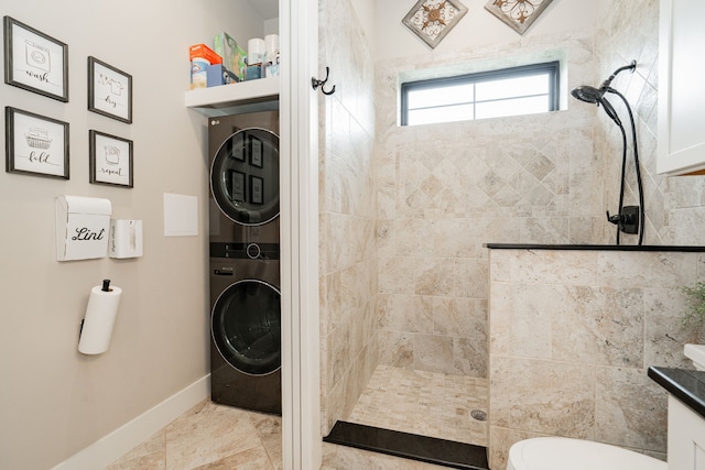 full bathroom with toilet, stacked washer and dryer, baseboards, and walk in shower