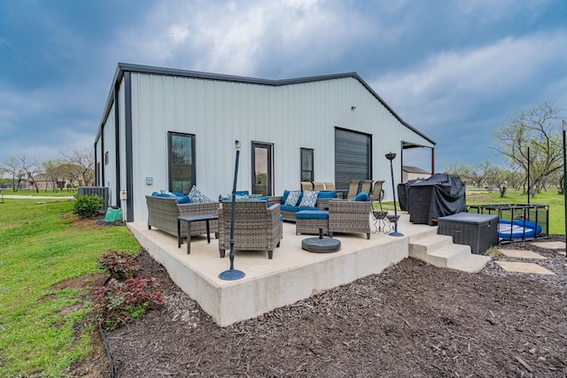 rear view of house featuring an outdoor living space, board and batten siding, cooling unit, a yard, and a patio area