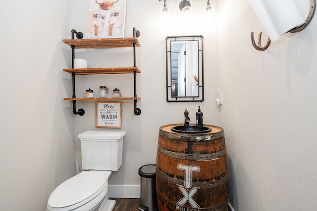 bathroom with toilet, vanity, baseboards, and wood finished floors