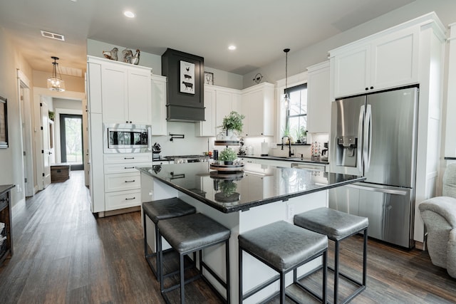 kitchen featuring visible vents, dark countertops, a kitchen breakfast bar, and appliances with stainless steel finishes