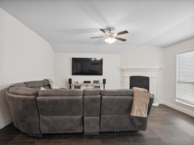 living area with baseboards, a ceiling fan, vaulted ceiling, and a fireplace