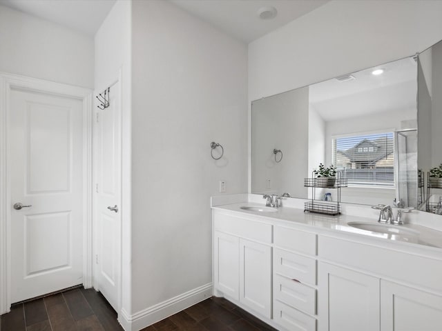 bathroom with wood finished floors, a sink, double vanity, and a stall shower