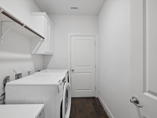 clothes washing area with washer and dryer, cabinet space, dark wood finished floors, baseboards, and visible vents
