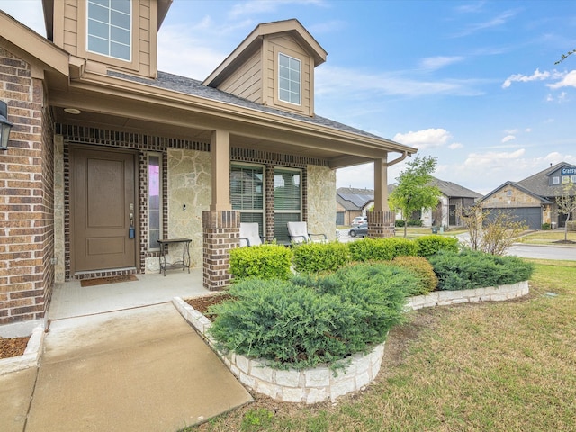 doorway to property featuring a porch and brick siding