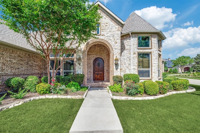 1891 Fostermill Dr, Prosper, TX 75078 - view of front of property with stone siding, a front yard, brick siding, and roof with shingles