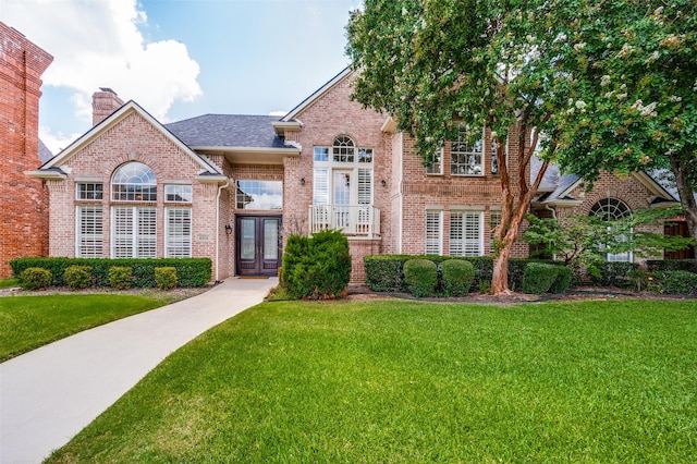 4816 Cape Coral Dr, Dallas, TX 75287 - traditional home featuring a front lawn, a chimney, a shingled roof, and brick siding