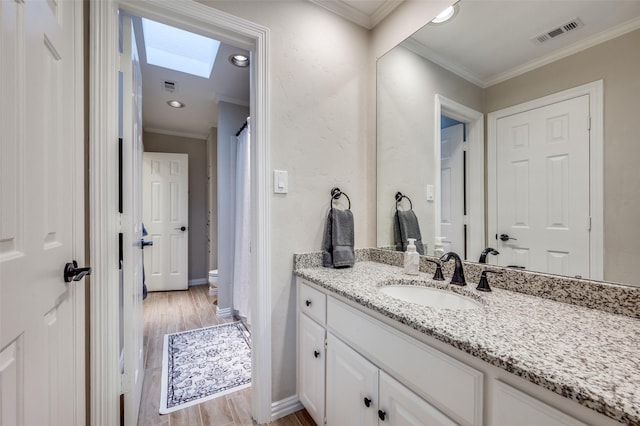 4816 Cape Coral Dr, Dallas, TX 75287 - full bathroom featuring vanity, ornamental molding, a skylight, visible vents, and wood finished floors