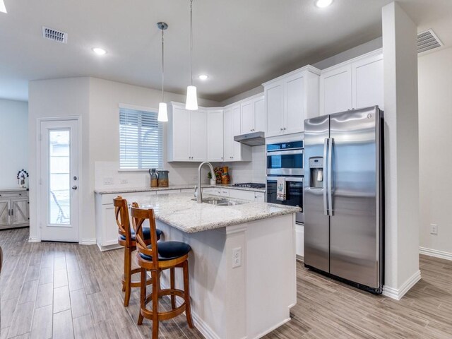 kitchen with white cabinets, appliances with stainless steel finishes, a sink, light wood-type flooring, and visible vents