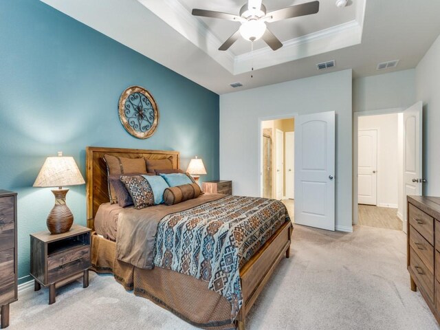 bedroom featuring a tray ceiling, visible vents, and light carpet