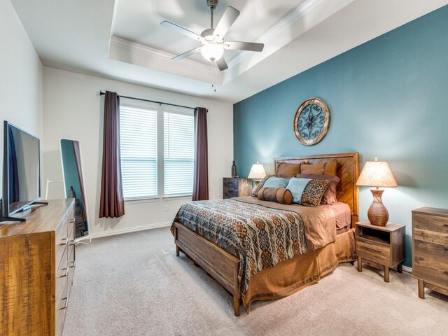 carpeted bedroom featuring crown molding, baseboards, ceiling fan, and a tray ceiling