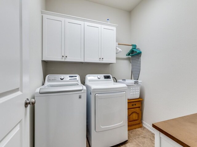 laundry room with cabinet space, light tile patterned floors, and washing machine and dryer