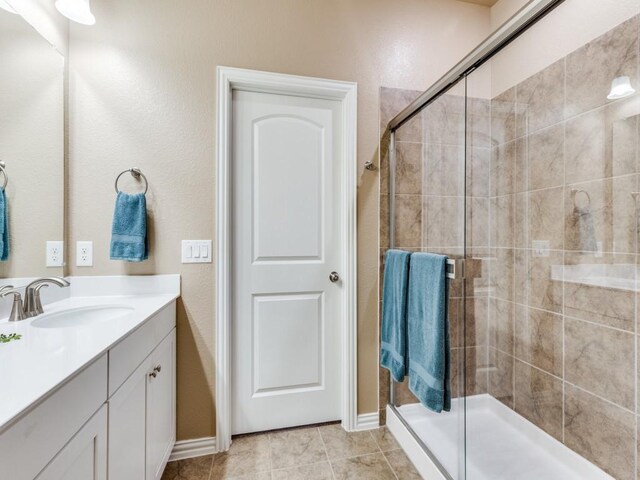 full bath with vanity, tile patterned floors, baseboards, and a stall shower