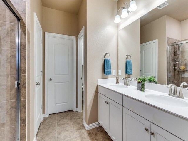 bathroom featuring visible vents, a sink, double vanity, and a shower stall