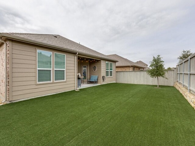 back of property featuring a yard, a fenced backyard, and a patio area