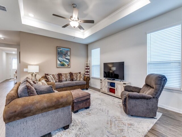 living room with baseboards, ornamental molding, a ceiling fan, and wood finished floors