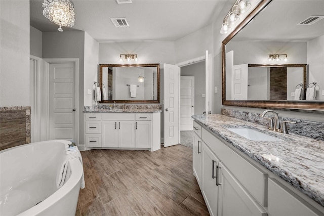 12756 Aspen Springs Ln, Fort Worth, TX 76052 - full bath with a soaking tub, a sink, visible vents, two vanities, and wood finished floors