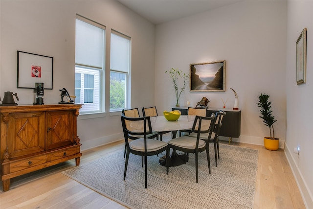 dining space with baseboards and light wood-type flooring