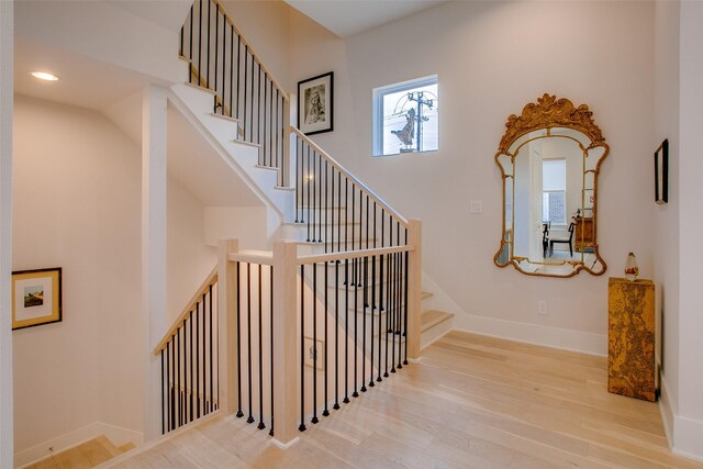 stairway featuring baseboards, wood finished floors, and recessed lighting