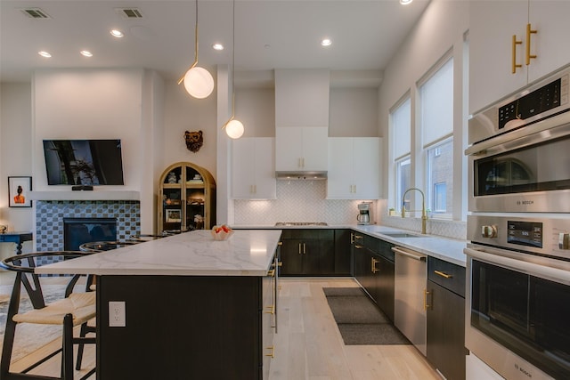 kitchen with appliances with stainless steel finishes, visible vents, a center island, and a sink