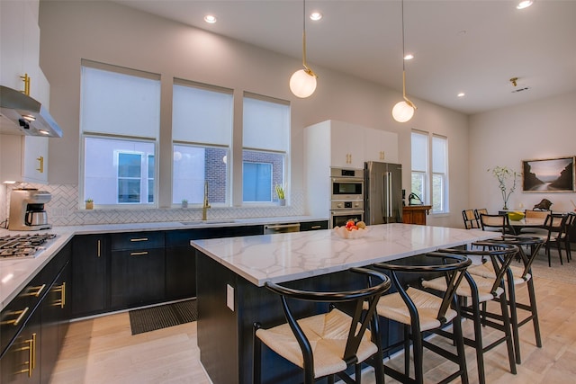 kitchen with a kitchen bar, a center island, appliances with stainless steel finishes, and dark cabinets